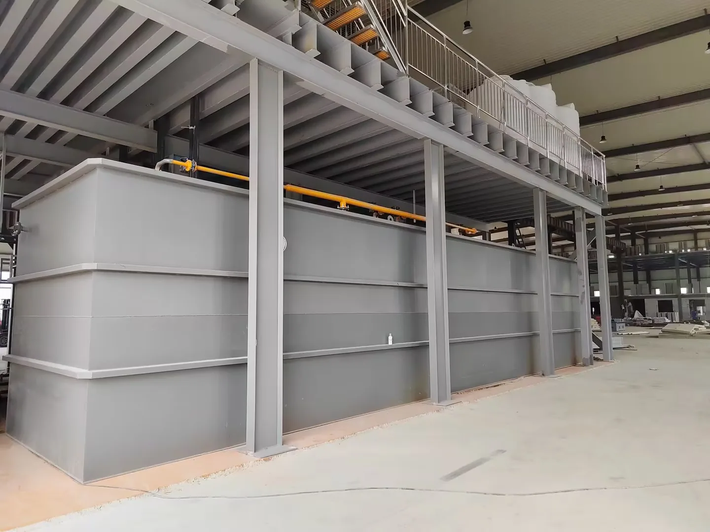 Large rectangular process tank installed beneath an elevated steel platform