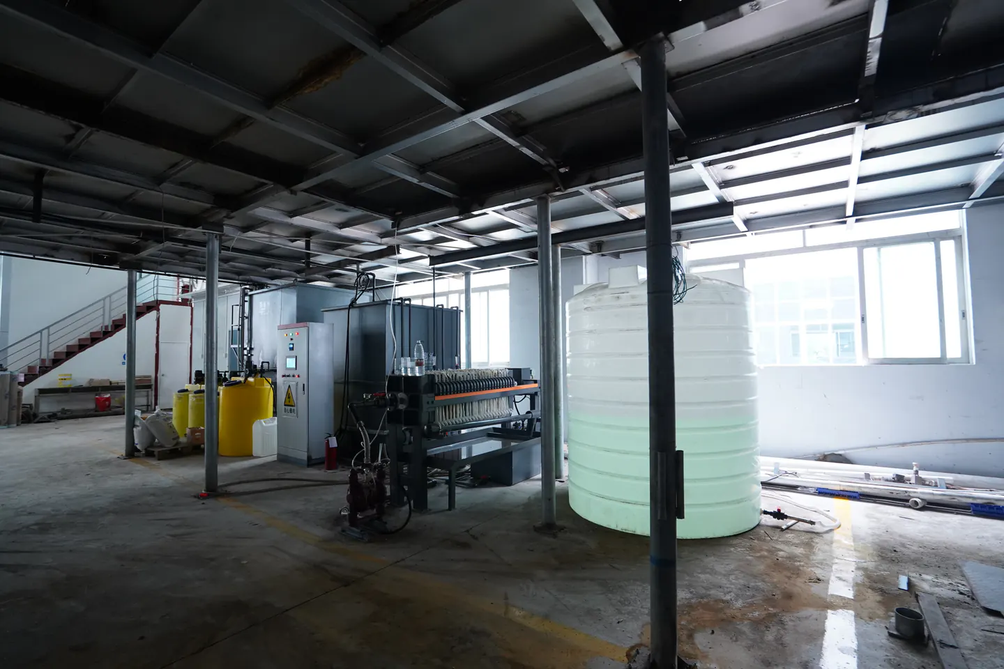 Industrial metal wastewater treatment layout with filter press and storage tank